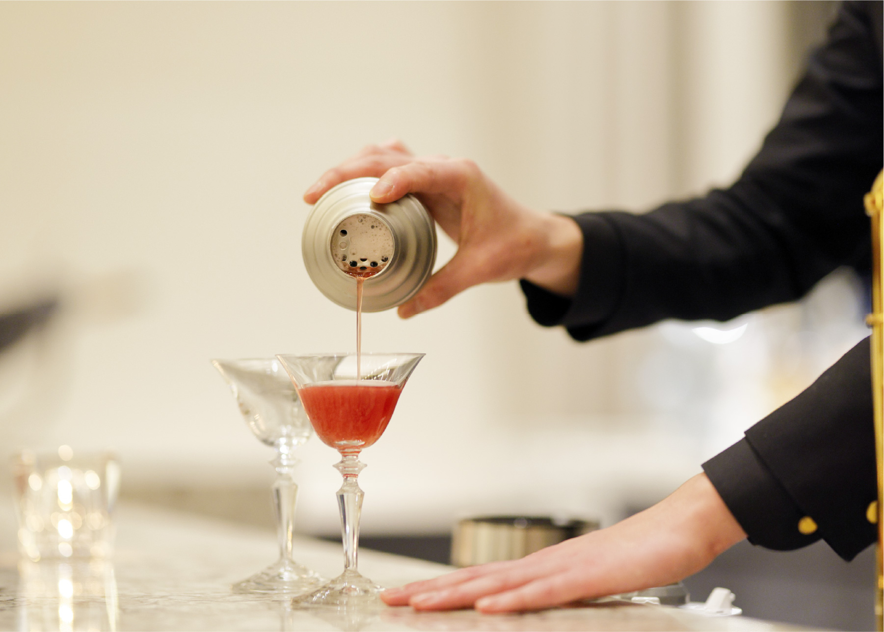 バーテンダーがグラスにお酒を注いでいる様子